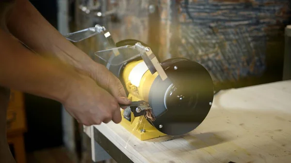 Electric sharpener and blade close up, hands cutting knife. Lense flare