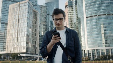 Moskova 'da elinde telefonla yürüyen genç adam, ağır çekimde.