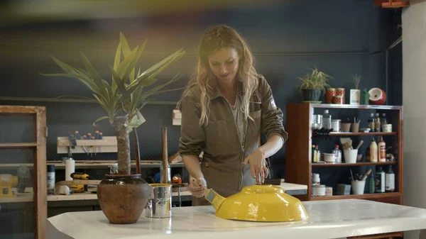 Atölyede sarı bir detayı boyayan bir kadın tamirci. İşaret fişeği — Stok fotoğraf