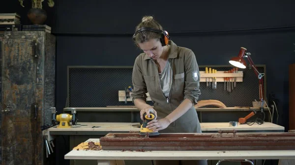 Молода жінка подрібнює дерев'яні двері, реставраційні роботи — стокове фото
