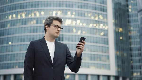 Homem de pé com um telefone no fundo do centro de negócios — Fotografia de Stock