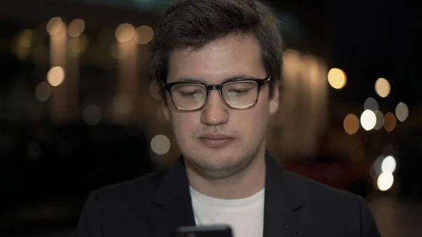 Empresário em óculos rolando o telefone no fundo, close-up — Fotografia de Stock