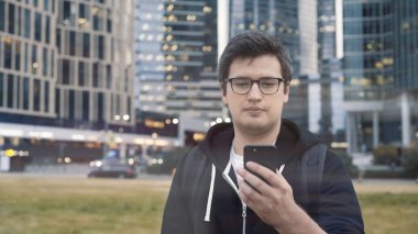 İş merkezinin arka planında telefonu olan bir adam, düşük açılı çekim.