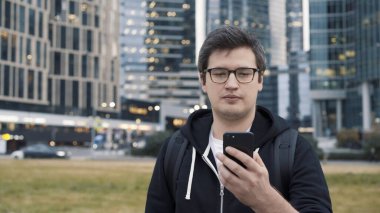 İş merkezinin arka planında telefonu olan bir adam, düşük açılı çekim.