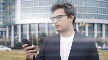 İş merkezinin arka planında telefonu olan bir adam.