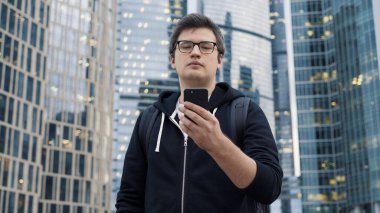 İş merkezinin arka planında telefonu olan bir adam, düşük açılı çekim.