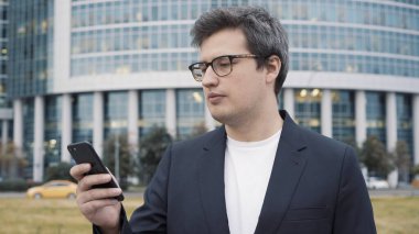 İş merkezinin arka planında telefonu olan bir adam.