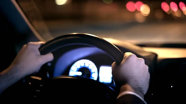 Mãos masculinas no volante, tiro no banco de trás com vista na estrada à noite — Fotografia de Stock