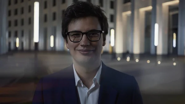 Homem feliz sorrindo em óculos e terno preto à noite, close up lente flare — Fotografia de Stock