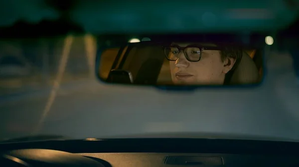 Conducente sorridente si riflette in uno specchietto retrovisore, strada notturna — Foto Stock