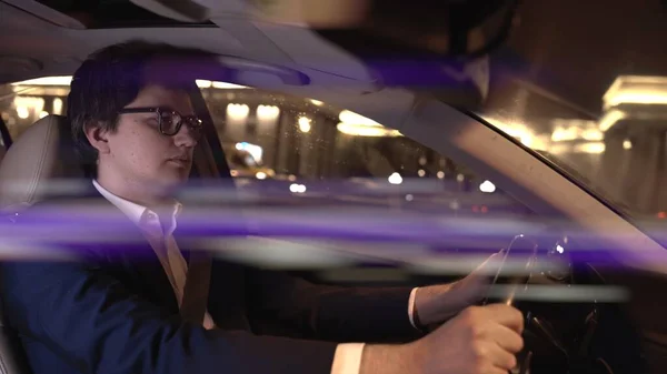 Man driver in black suit and eyeglasses at night, lens flare