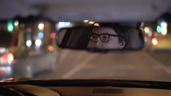 La cara del conductor se refleja en un espejo retrovisor, en el asiento trasero — Foto de Stock