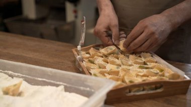 Un ve tortellini ile plastik tepsi, erkek ahşap tepsiyle aşçı elleri