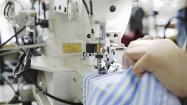 Makineye dikiş, ellere yakın ve mavi çizgili kumaş.