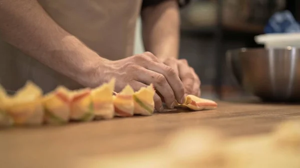 Manos masculinas que ponen tortellini en bandeja de madera, en mesa de cocina de madera —  Fotos de Stock
