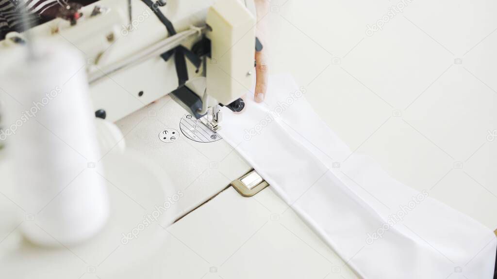 Pice of white cloth on white sewing machine, top view shot