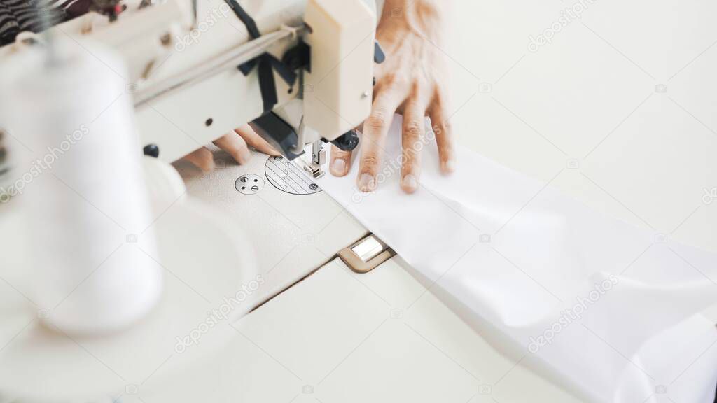 Female hands on white sewing machine, top view shot