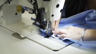 Makineye dikiş dikiyorum, ellerimi ve mavi bezimi kapatıyorum.