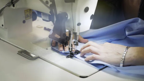 Sewing on machine, close up of hands and blue cloth lens flare — Stock Photo, Image