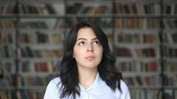 Estudiante asiático en camisa blanca sobre fondo de estanterías borrosas en la biblioteca — Foto de Stock