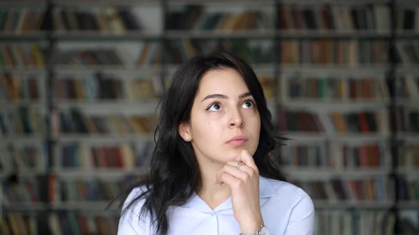 Asiatico studente in bianco camicia pensiero oltre su sfondo f librerie — Foto Stock