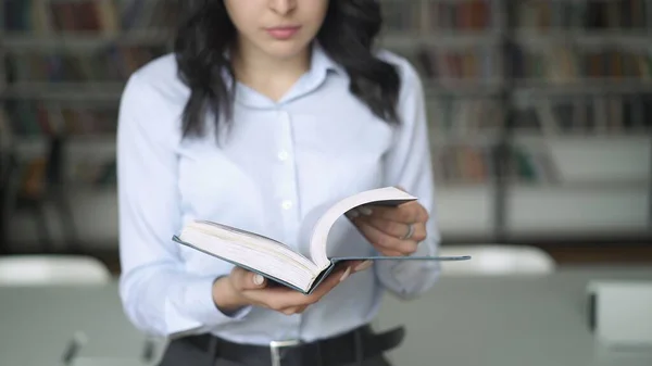 Giovane donna che tiene un grande libro sullo sfondo di librerie sfocate — Foto Stock