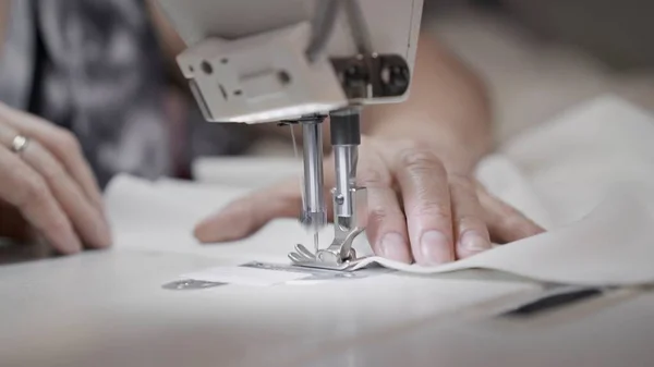 Sewing white cloth on a white sewing machine close up, female hands — Stock Photo, Image