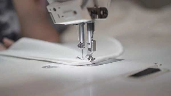 Sewing white cloth on a white sewing machine close up, blurred background — Stock Photo, Image