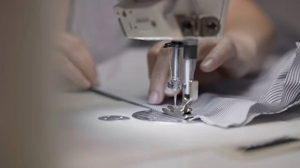 Sewing striped shirt on a white sewing machine close up, female hands — Stock Photo, Image