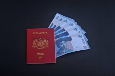 Cumhuriyeti Endonezya Rupiahı notlar koyu arka plan üzerine Malezya pasaportu ile.