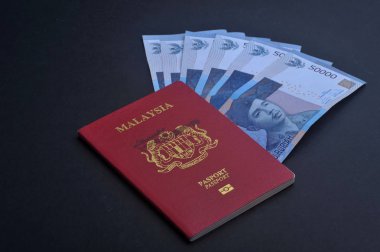 Cumhuriyeti Endonezya Rupiahı notlar koyu arka plan üzerine Malezya pasaportu ile.