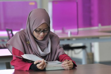 Genç ve güzel bir muslimah öğrenci kütüphanede yalnız çalışıyor..