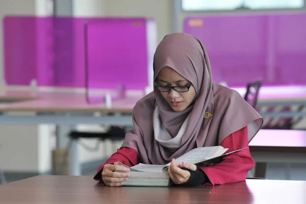 図書館で一人で勉強する美しい若いイスラム教徒の学生 — ストック写真