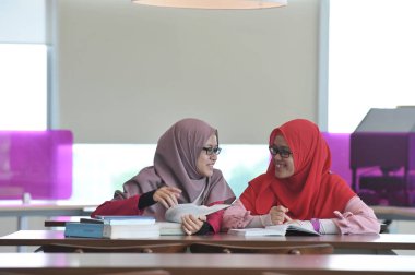 İki güzel genç Muslimah öğrenci görevlerini tartışıyor..