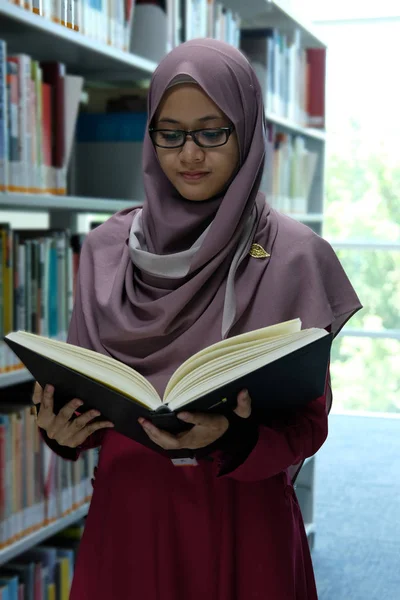 図書館の本棚から本を選んで本を読んだ美しい若いヒジャーブの女性 — ストック写真
