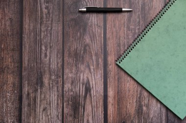 Üzerinde kalem ve defter olan bir ofis masası düz bir görünümde görünürName.