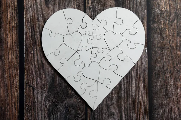 Love shape white puzzle on top of wooden table. Love and caring conceptual.