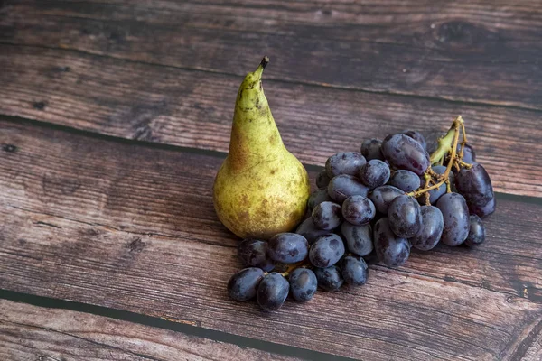 Konferenzbirne auch als Pyrus communis bekannt und kernlose rote Traube auf dem Holztisch. — Stockfoto