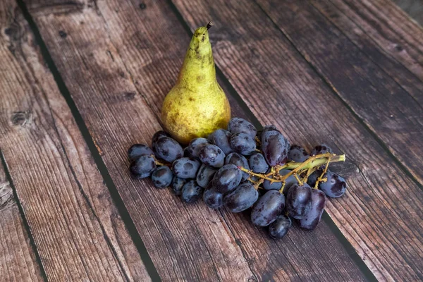 Konferenzbirne auch als Pyrus communis bekannt und kernlose rote Traube auf dem Holztisch. — Stockfoto