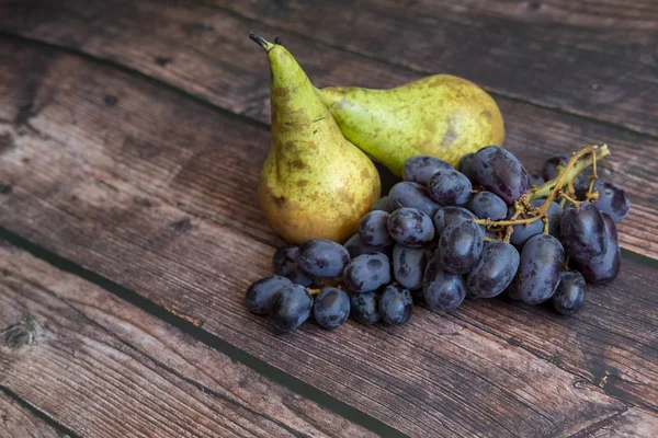 Konferenzbirne auch als Pyrus communis bekannt und kernlose rote Traube auf dem Holztisch. — Stockfoto