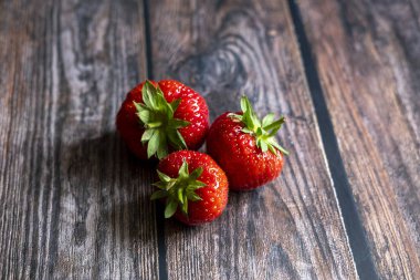 Tahta masanın üstünde taze kırmızı İskoç çilekleri..