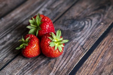 Tahta masanın üstünde taze kırmızı İskoç çilekleri..