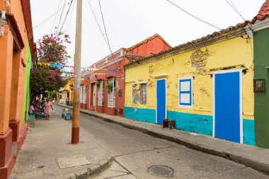 Cartagena, Kolombiya - 24 Mayıs: Kimliği belirsiz kişi yürüyüş açık renklerle boyalı sömürge dönemi evleri Cartagena, Kolombiya üzerinde 24 Mayıs 2016 Getsemani Mahallesi'nde geçmiş.