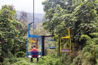 Manizales, Kolombiya - Haziran 1: Açık renklerle boyalı teleferik Recinto del Pensamiento tabiatı Manizales, Kolombiya yakınındaki 1 Haziran 2016 üzerinde ormanın içinden kimliği belirsiz kişi binmek.