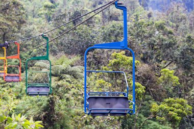 Mavi, yeşil turuncu ve sarı renkli sandalyeler teleferik Recinto del Pensamiento tabiatı yakınındaki Manizales, Colombia.