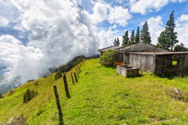 Bir çit arka plan ve bir abandonded çimento evindeki bulutlar ile mesafe içine bir ridgetop Quindio ve: Tolima, Colombia arasında kaybolur. 
