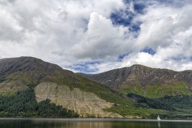 Loch Lochy İskoçya'nın dağlık alanındaki suların üzerinde küçük beyaz Yelkenli tekne.