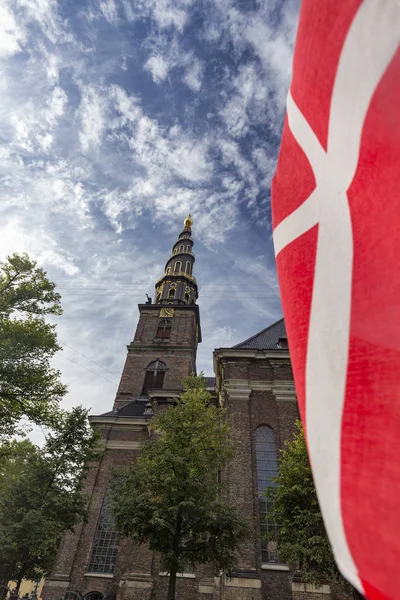 Portrait view of a Danish flag and the Church of our Savior in Copenhagen, Denmark.
