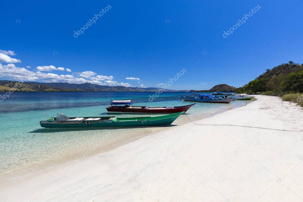 Boats on a white sand beach on a large Island in the Seventeen Island National Park, Flores, Indonesia. 