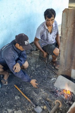 Luang Prabang, Laos - 8 Ekim: Isı iki kimliği belirsiz erkek kömürlerin Luang Prabang, Laos üzerinde 8 Ekim 2017 yılında köy demirhane, bir bıçak yukarıya.
